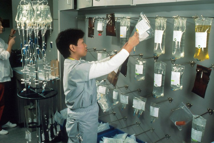 Image of an Asian female nurse hanging bags of chemotherapy drugs.